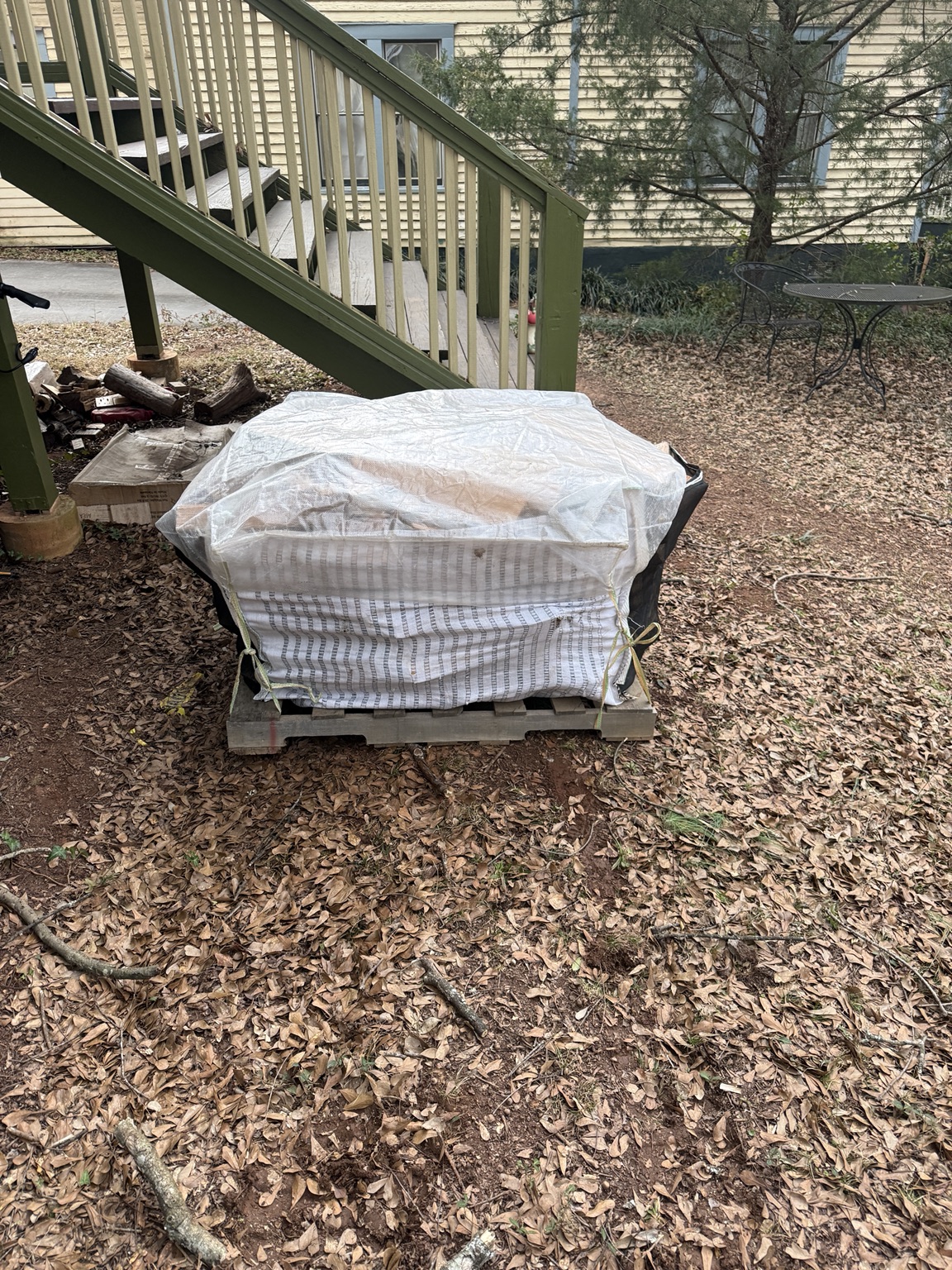 Rain cover protecting a large firewood bag on a pallet